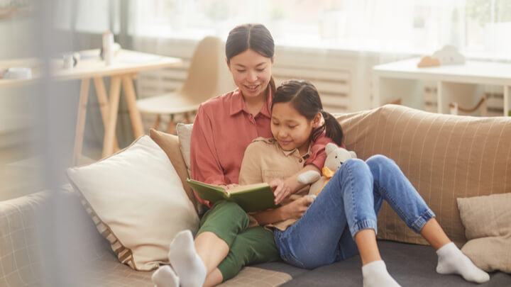 family_home_reading_couch_mother_daughter-w720h405