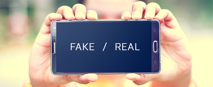 2 mains tiennent un téléphone qui montre un écran sur lequel est écrit fake / real