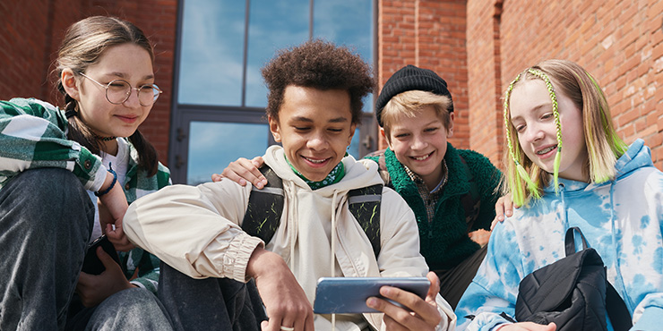 un groupe de 4 jeunes de la génération alpha regarde un téléphone