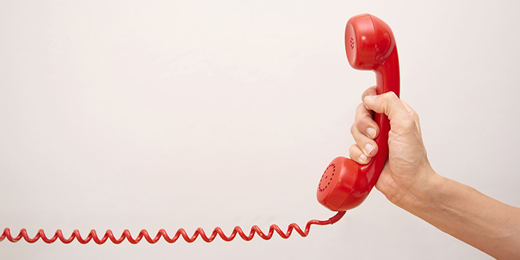 téléphone filaire rouge tenu par une main